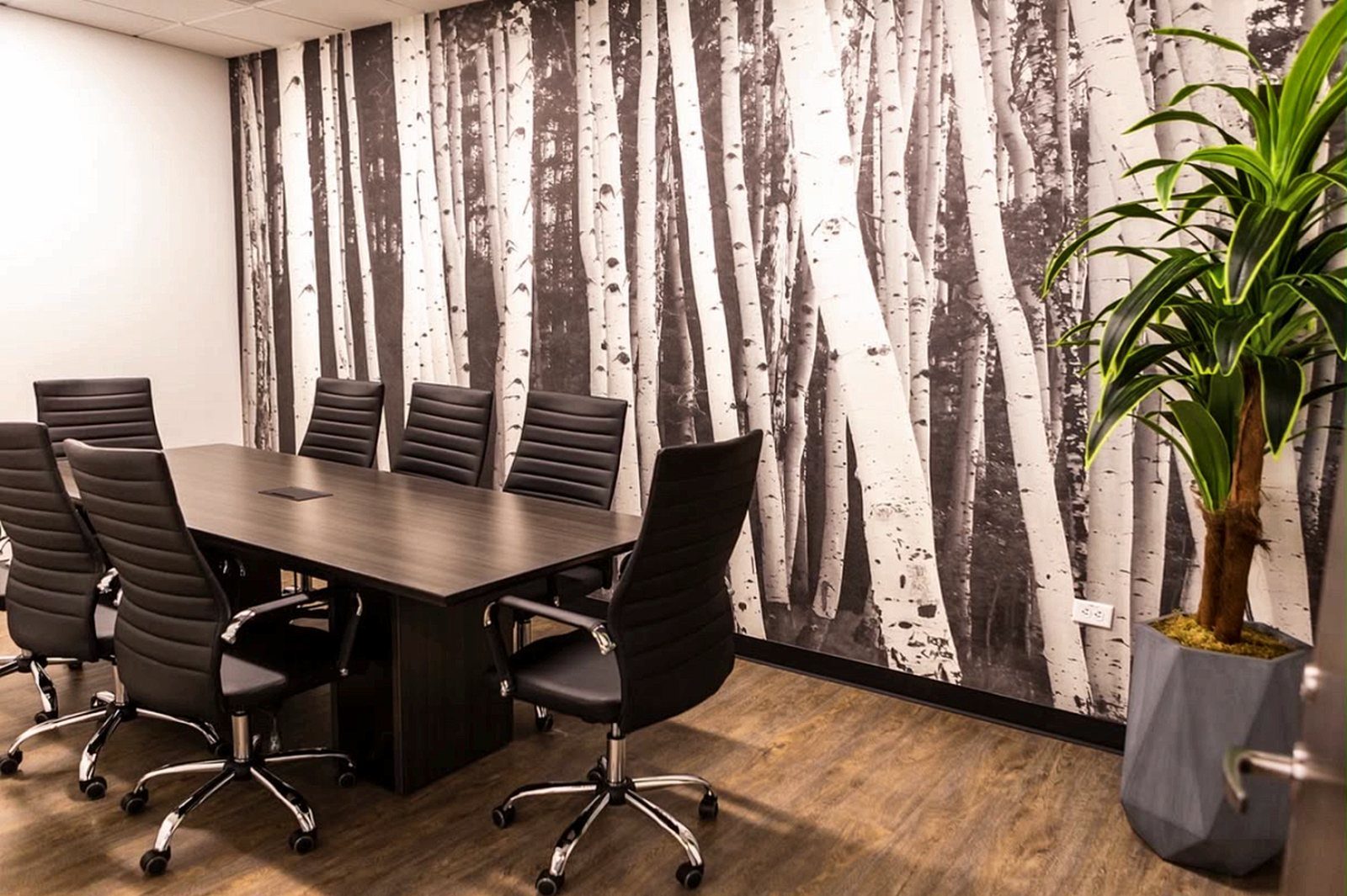 Conference table with black leather chairs beside floor-to-ceiling windows