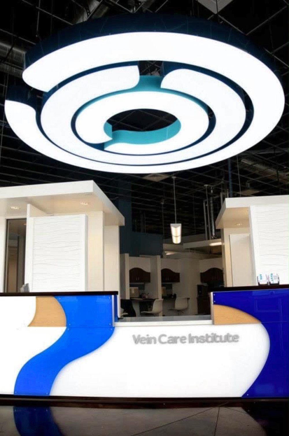 Clinic reception desk in white and blue under a large circular light fixture